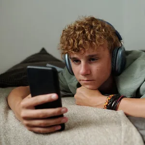 Hatespeech: Jugendlicher im Bett am Handy Hatespeech: Jugendlicher im Bett am Handy