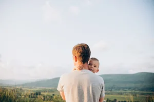 portrait d’un père tenant un enfant dans ses bras, vu de dos Séparation : un père avec son enfant