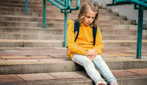 Schulwechsel. Junges Mädchen sitzt betrübt auf einer Treppe. Schulwechsel. Junges Mädchen sitzt betrübt auf einer Treppe.
