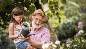 Little girl helping her grandpa watering plants Sommer: Ein Grossvater giesst mit seiner Enkelin Pflanzen