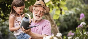 Little girl helping her grandpa watering plants Sommer: Ein Grossvater giesst mit seiner Enkelin Pflanzen