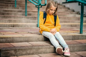 Changement d'école. Une jeune fille est assise sur un escalier, l'air triste. Changement d'école. Une jeune fille est assise sur un escalier, l'air triste.