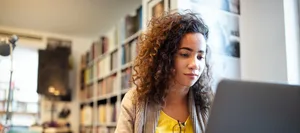 Une jeune et jolie étudiante qui travaille et étudie à la bibliothèque de l’université L'IA pour postuler à un emploi ? Une jeune fille est assise devant son ordinateur portable