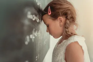 Header_ADHS_Hochsensibilit_t Ein Mädchen stützt ihren Kopf auf eine Schultafel ab. Hochsensible können schüchtern und extrovertiert sein.