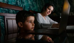 Mother Working At Home While Her Bored Son Look At Laptop Screen Nonstop-Unterhaltung: Kind starrt in Laptop