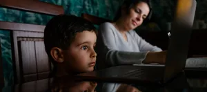 Mother Working At Home While Her Bored Son Look At Laptop Screen Nonstop-Unterhaltung: Kind starrt in Laptop