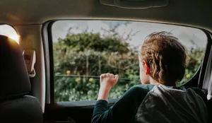 Young boy in the back of a car looks out of the window on a sunny day Trennung: Ein Junge schaut aus einem fahrenden Auto