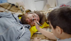 Mischievous boy painting face of father sleeping on couch at home Faule Eltern: Interview mit Hodkinson