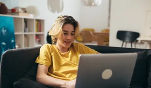 teenager boy laying on couch at home and using laptop computer Kann KI in der Berufswahl unterstützen? Ein Junge sitzt an seinem Laptop.