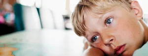 09_20_Verträumte_Kinder_Dossier_Hauptteil_HL Verträumte Kinder unter Druck: Bub legt Kopf auf den Pult und schaut gedankenverloren in die Ferne