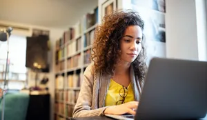 Una giovane e bella studentessa che lavora e studia nella biblioteca dell’università L'intelligenza artificiale per la candidatura? Una ragazza è seduta davanti al suo portatile