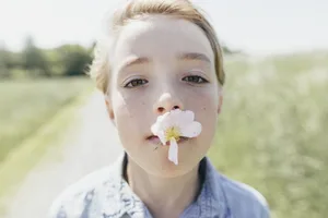 Ritratto di un ragazzo con un fiore in bocca Bambino con un fiore in bocca