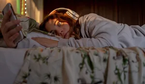 26-10-cyberharcèlement-Swisscom-magazine-suisse-des-parents-hg Une jeune fille est allongée dans son lit, avec des écouteurs et son smartphone