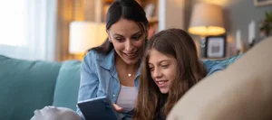 Mother and daughter bonding over technology at home Mutter und Tochter schauen gemeinsam Inhalte auf dem Smartphone an