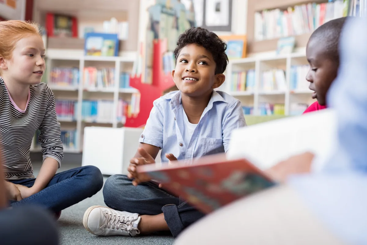 Les enfants écoutent des histoires Lire : trois enfants à l'école primaire écoutent attentivement une histoire
