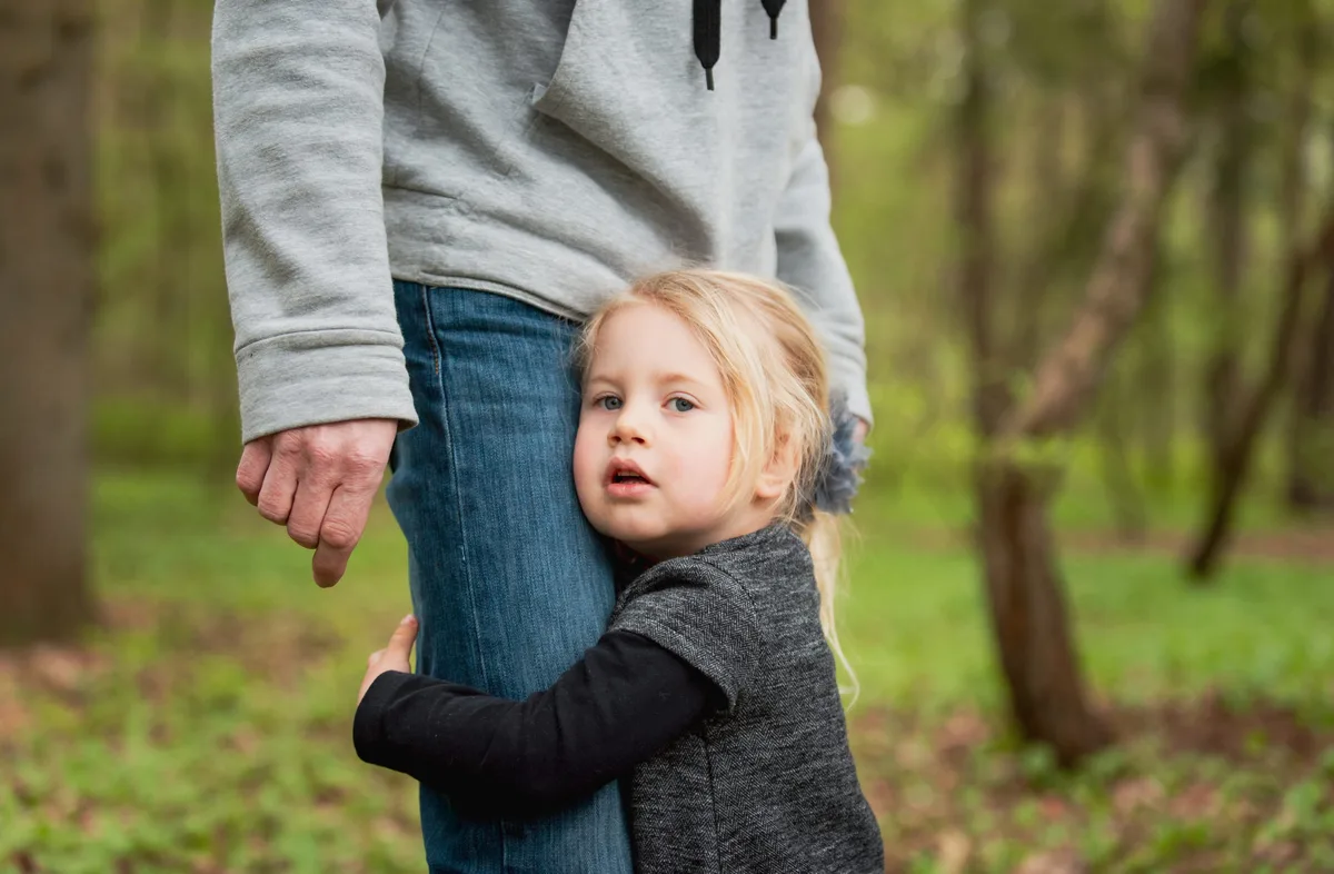 frisch-fotografie.de Une petite fille s'accroche à la jambe de son père